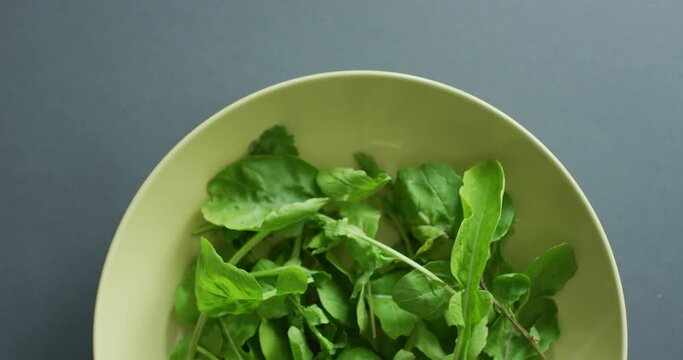Video of close up of bowl of fresh salad leaves on grey background