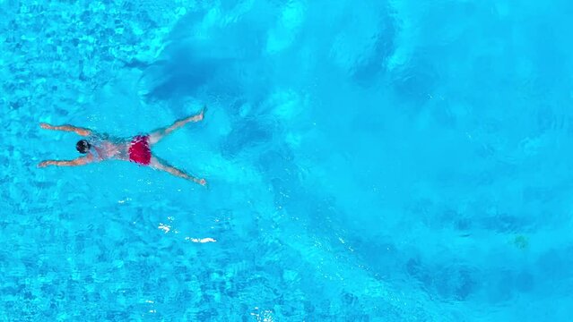 Aerial view as a man dives into the pool and swims