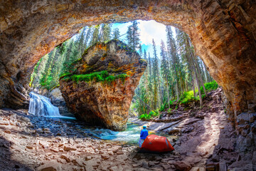 Hiker outside his camping tent at Hidden Cave with waterfall and limestone bedrock in Johnston...