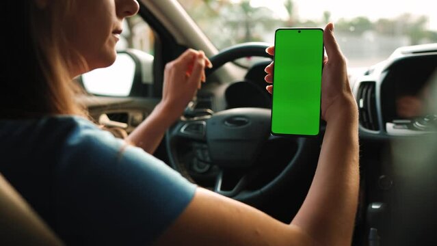 Female driver using a smartphone inside the car. Chromakey smartphone with green