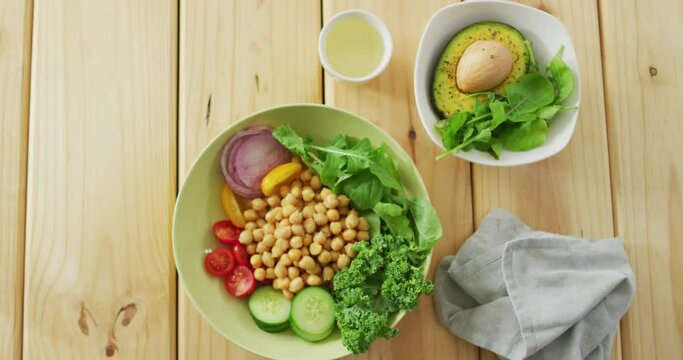 Video of bowls of fresh salad with green leaves on wooden background