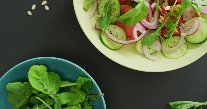 Video of fresh salad with green leaves and bowl with salad leaves on grey background