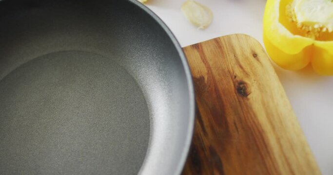 Video of fresh vegetables and nuts around frying pan with copy space on wooden background