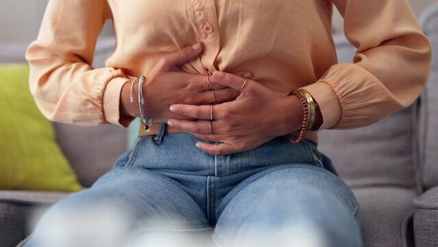 Stomach pain, digestion and sick with woman on sofa for menstruation cramps, constipation and virus. Diarrhea, nausea and inflammation with girl in living room at home for illness with abdominal ache