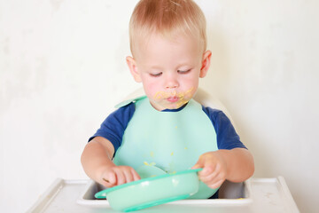 kid eats with a spoon and learns by himself
