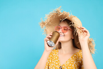 Beautiful happy woman drinking from beverage can on light blue background. Space for text