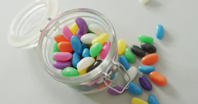 Video of multicoloured jelly sweets in glass jar on white background