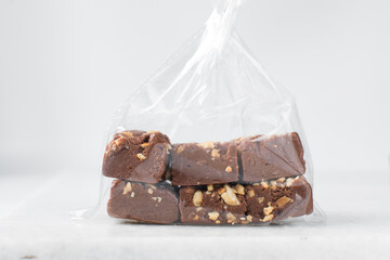 chocolate fudge with nuts in a cellophane bag, chocolate fudge cut into pieces, fudge candy on a marble tray
