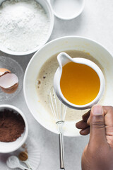 Pouring melted butter into a white mixing bowl
