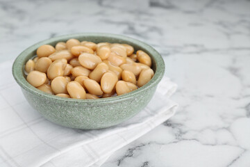 Bowl of canned kidney beans on white marble table, closeup. Space for text