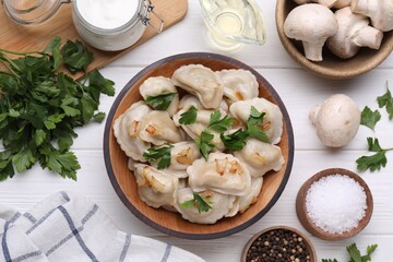 Delicious dumplings (varenyky) with potatoes, onion and parsley served on white wooden table, flat...