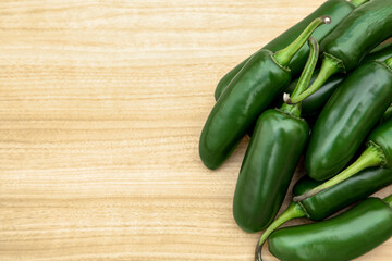 Fresh ripe green jalapeno peppers on wooden table, flat lay. Space for text