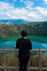 Fototapeta premium Mujer latina pelo negro observando una laguna color esmeralda en un dia soleado