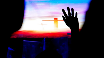 Hand raising, blurred christian cross background. 