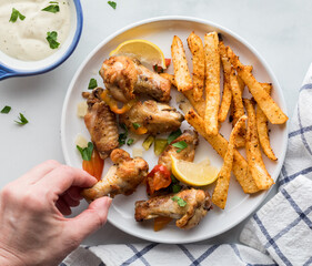 A plate of crispy chicken wings served with seasoned jicama fries and dip.