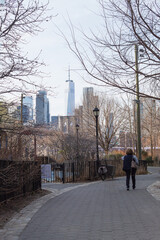 Unrecognizable woman walking through brooklyn bridge park with new york skyscrapers in the background