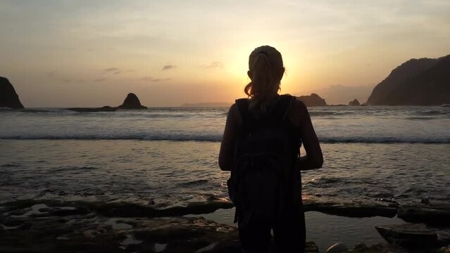 A woman enjoy beautiful sunset at Papuma beach in Jember, East Java, Indonesia.