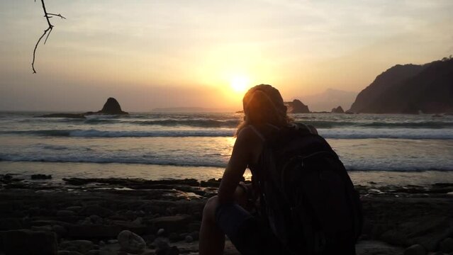 A woman enjoy beautiful sunset at Papuma beach in Jember, East Java, Indonesia.