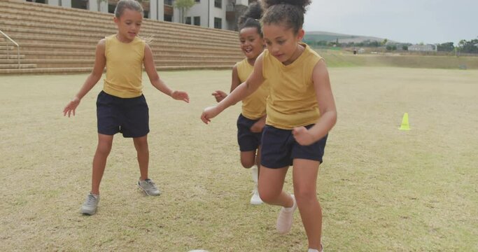 Video of happy diverse girls playing soccer in front of school