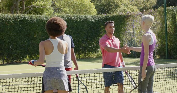 Happy diverse group of friends shaking hands at tennis court