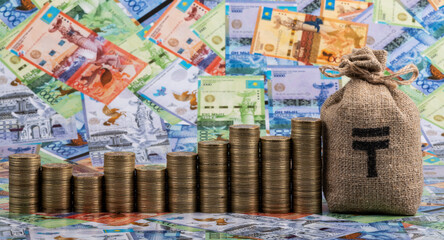 Columns of many coins in denominations of 100 Kazakhstani tenge against the background of Kazakhstani banknotes