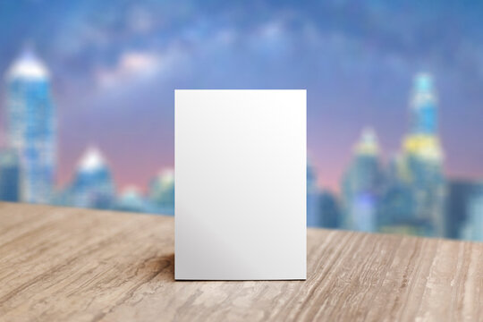 Mock up Label the blank menu frame in Bar restaurant. Stand for booklet with white sheet paper acrylic tent card on table wiht blurred nignt city background