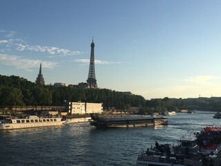 Photo of the Eiffel Tower in Paris, France overlooking  La Seine River and a boat cruise. 