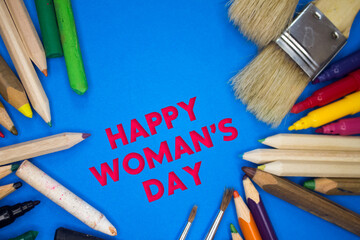 Overhead shot of school supplies with Happy Woman's Day text. Brushes, pencils, artistic tools. Art And Craft Work Tools.
