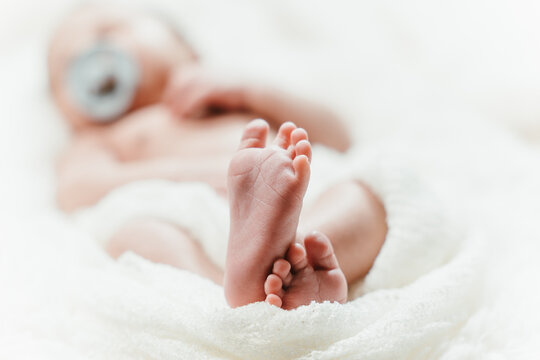 Close-up (macro photo) of newborn feet with white blanket around