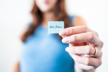 woman holding gender identity pronouns She Her on paper speech bubble, respecting people's identity in society