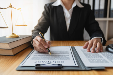 Asian female legal advisor or a lawyer using a pen to check business information and various...