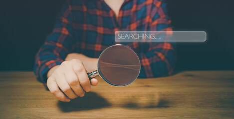 Hand holding magnifier glass with search bar icon for SEO or Search Engine Optimisation wording...