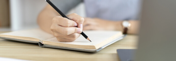 Asian woman taking notes in notebook while studying online in laptop at home, Video chat, Online communication , Stay home, New normal, Distance learning., Social distancing, Learn online..