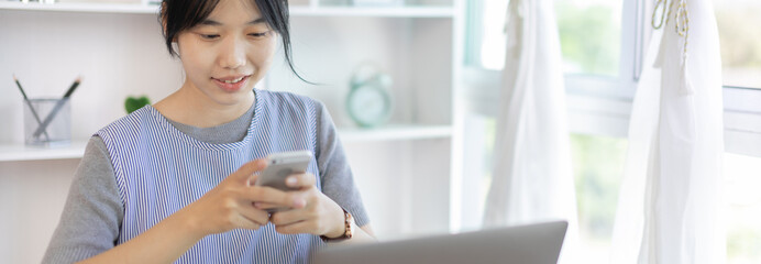 Asian woman having fun playing games on mobile phone, Play games on the sofa in the living room on weekends, Resting at home, Comfort zone, Touch screen mobile phone.