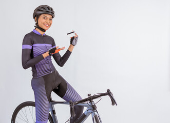 asian woman in cycling outfit showing tha blank card while sitting on the bike on isolated...