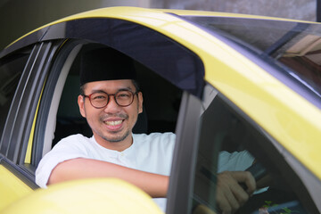 Moslem Asian man smiling at the camera when driving his car