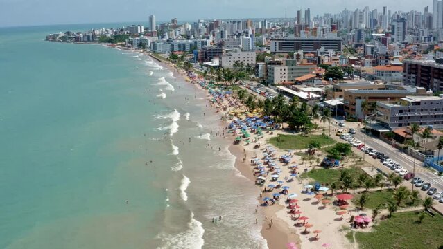 Rising aerial shot of intermares beach in Cabedelo, Brazil with Brazilians and tourists enjoying the ocean near the costal capital of Joao Pessoa in the state of Paraiba on a warm sunny summer day.