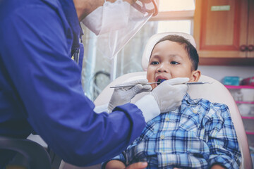 Dentist examines child's teeth using metal instruments at dental clinic. Dentistry and healthcare concept