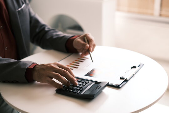 The accountant works on calculating costs and profits on the annual balance sheet with a calculator.