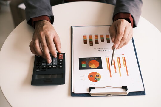 The accountant works on calculating costs and profits on the annual balance sheet with a calculator.