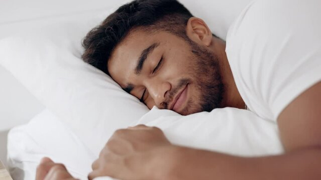 Face of happy man sleeping in bed, morning and at home for relaxing wellness, comfortable pillow and healthy rest. Young guy asleep in bedroom with smile, happiness and peaceful dreams on mattress