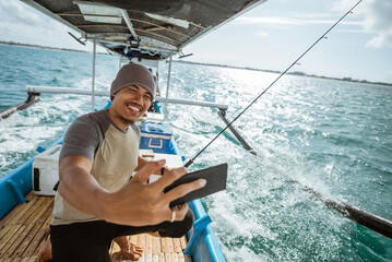 fisherman selfie while fishing with a small fishing boat at sea