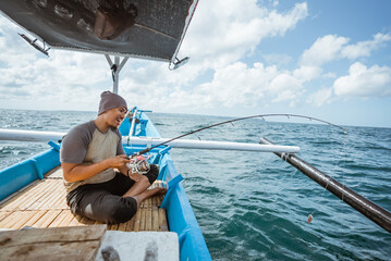Asian fishermen pull in fishing rods during hook ups while sea fishing