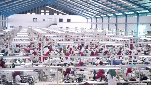 Big sewing machine factory crowded Factory employee. Worker activity in a textile factory. factory worker sewing gloves using modern sewing machines
