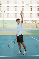 male tennis player smiling and waving after the match on the tennis court