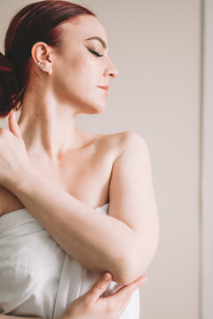 Photo shoot for women's day. The girl lies on the sheet. Naked female body in a sheet. Girl and orchids. Girl with flowers.