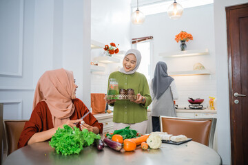 muslim woman serving drink for her friend and family at home having dinner together