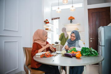 woman wearing hijab with best friend preparing food for dinner in the kitchen