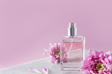 Obraz na płótnie Canvas a chic bottle of women's perfume or toilet water on a white marble podium with lilac flowers. front view. pink background. a copy space.