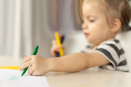 Adorable caucasian baby girl drawing greeting card for mothers day. Image with selective focus on hand